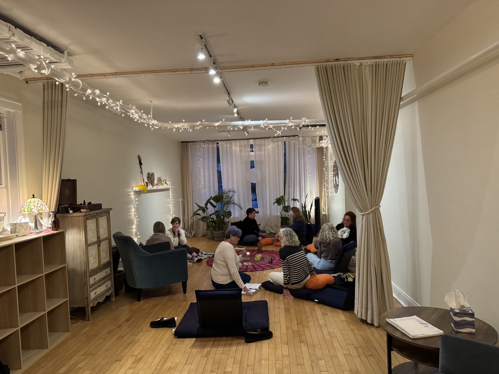 Evening circle of women seated around a mandala rug with candlelight