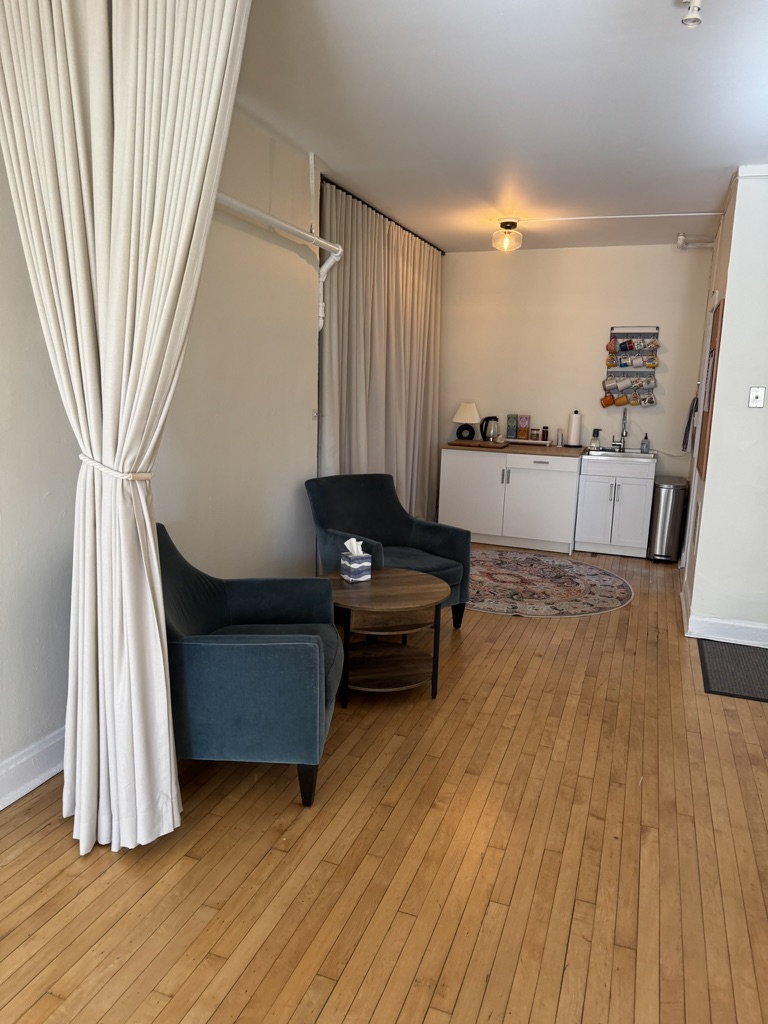 Studio lounge area with armchairs, side table, and kitchenette
